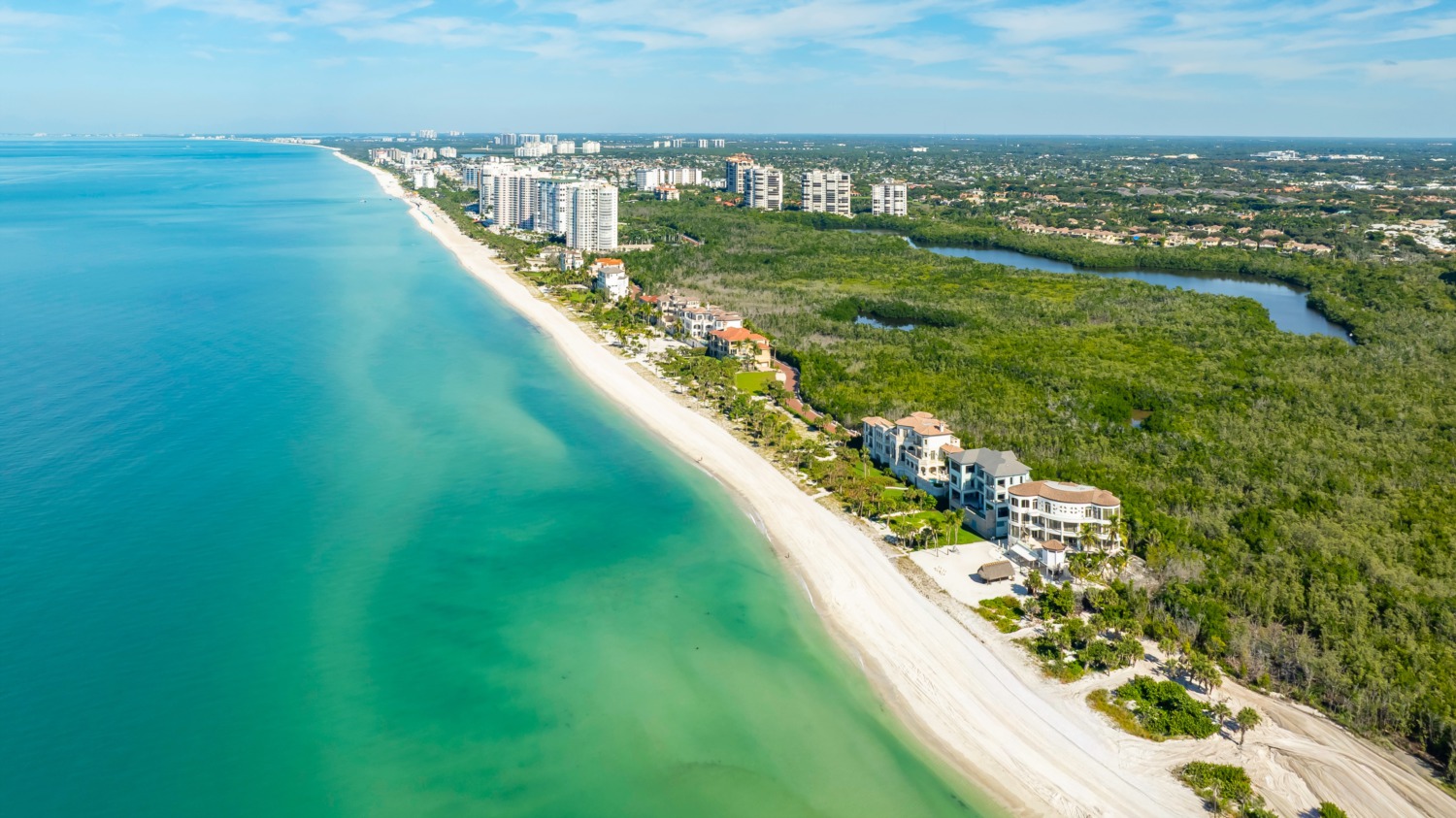 Aerial coastline view of beachfront high-rises and white sand shoreline