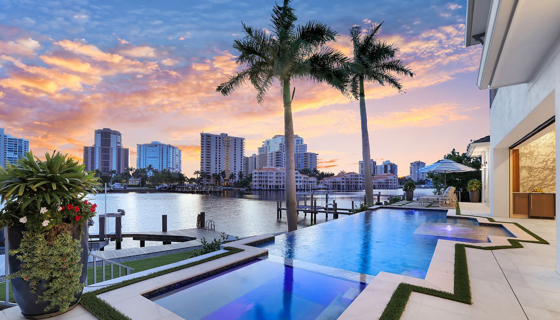 Waterfront home with infinity pool and city skyline at sunset