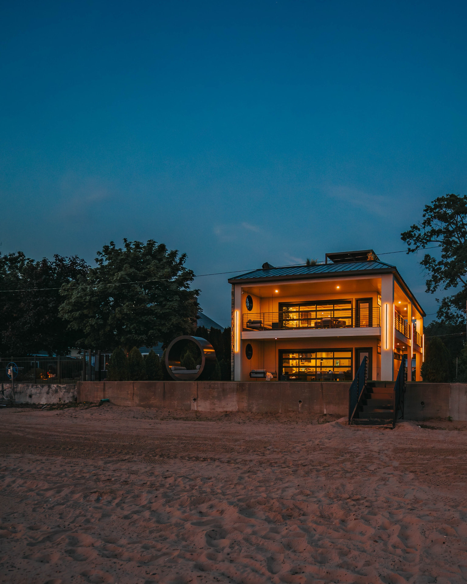 The villa viewed from the beach at nightfall with warm interior lighting