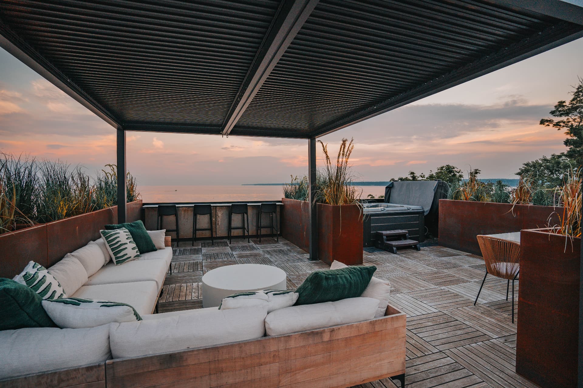 Rooftop terrace with louvered pergola, sectional seating, bar, and hot tub overlooking the lake