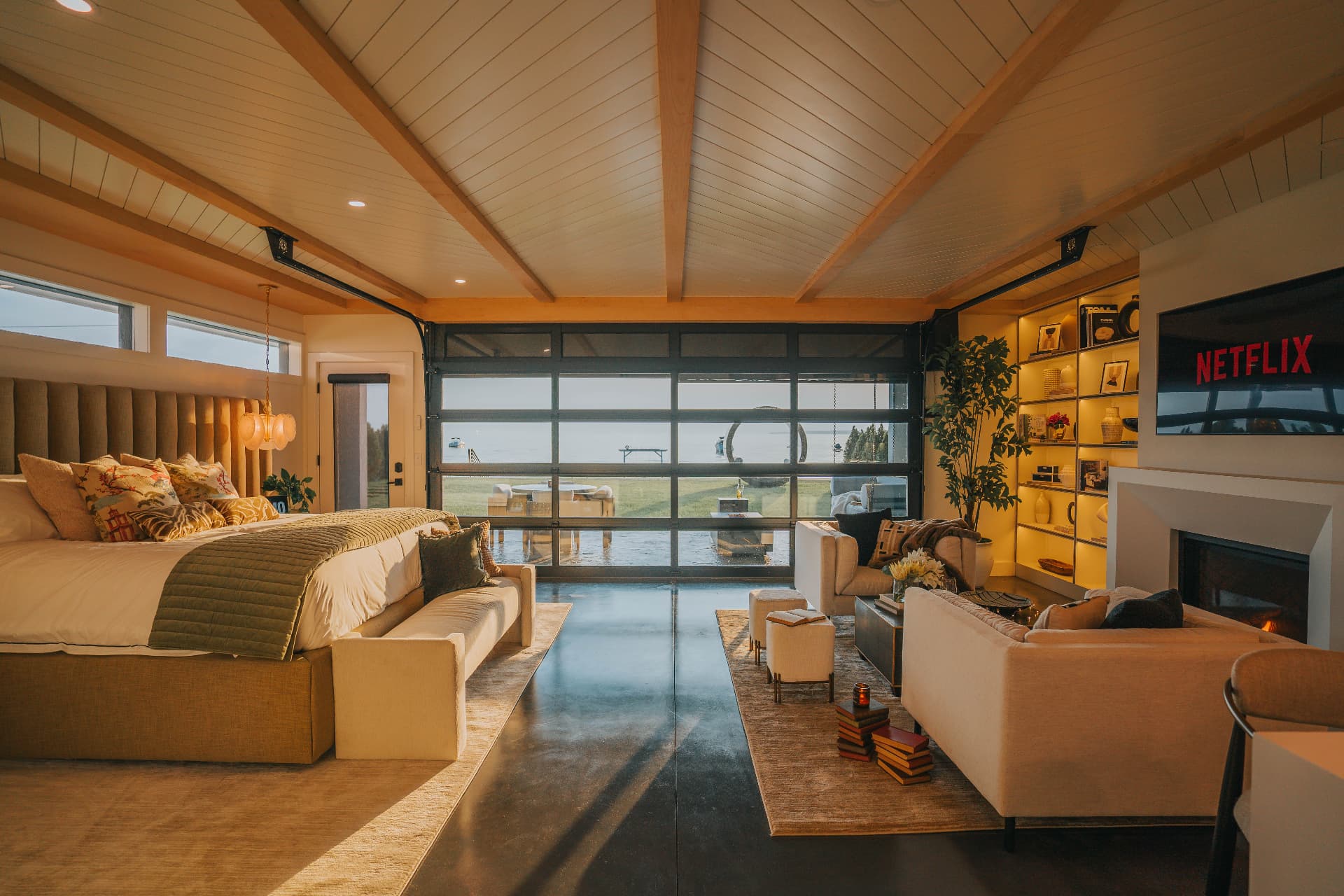 Living area at Park Ave Beach Villa with a full-height glass wall opening to Oneida Lake at dusk