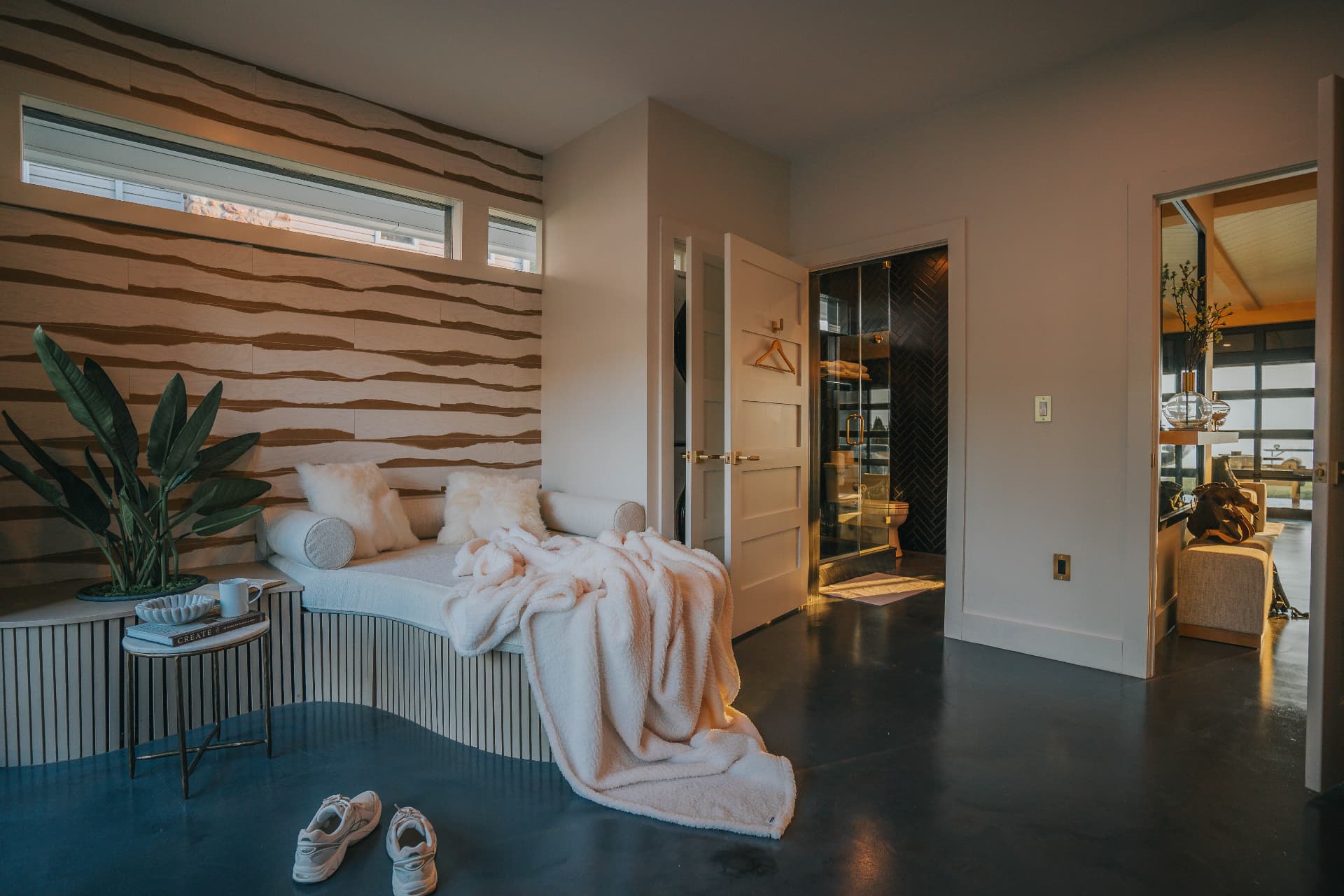Relaxation lounge with sculpted daybed, textured wood wall, and adjoining spa bath