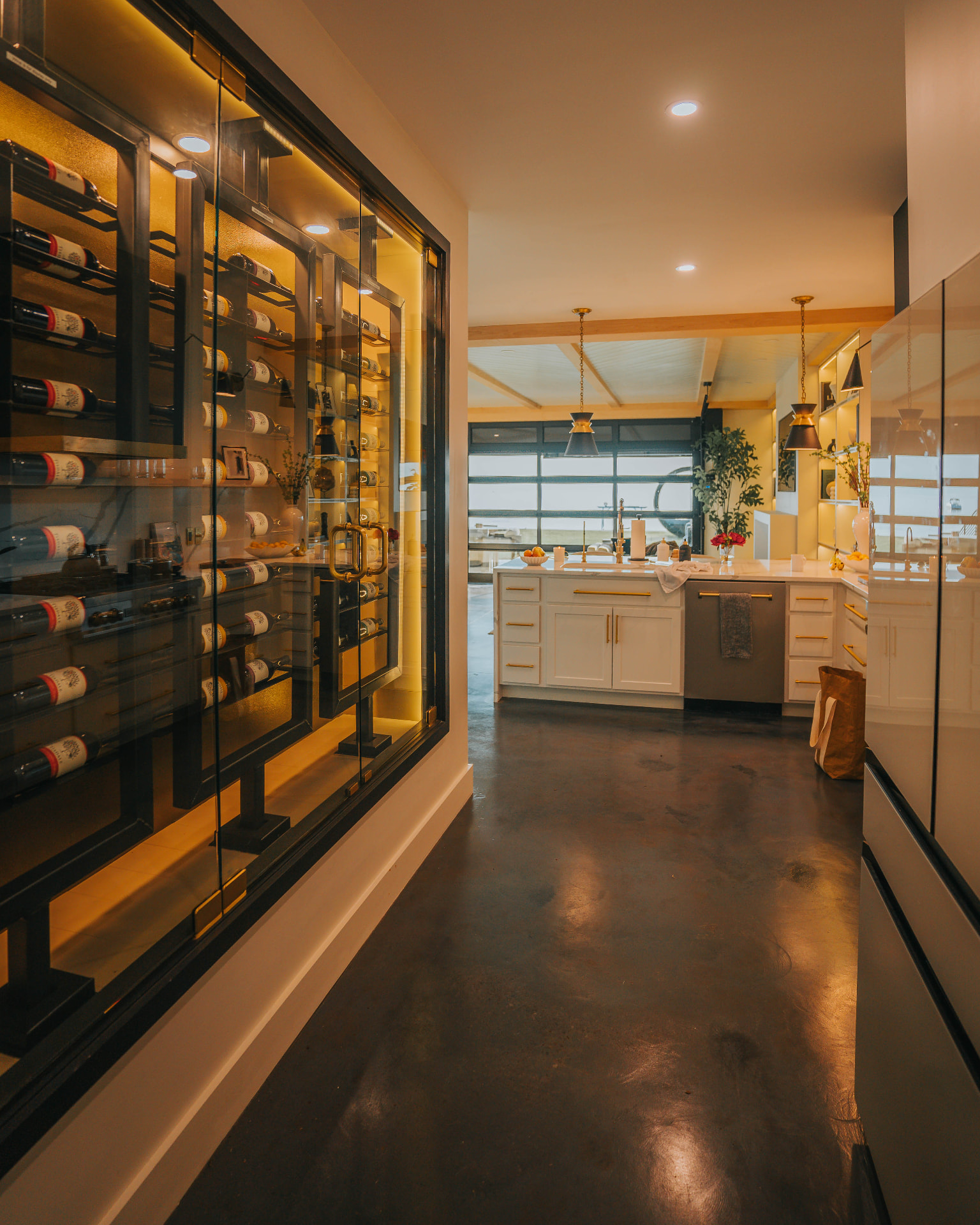 Illuminated glass-enclosed wine display leading toward the villa's kitchen