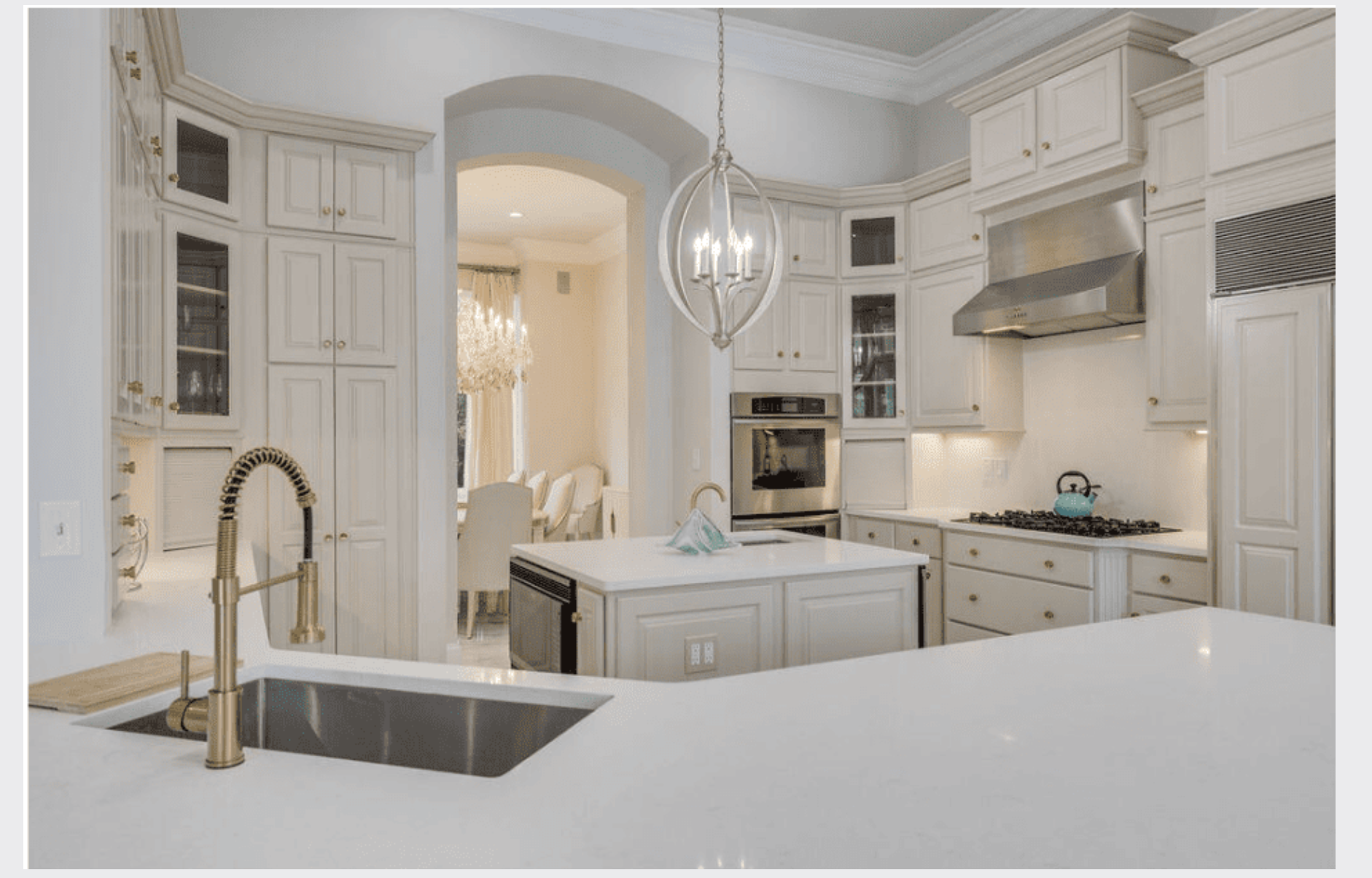 Gourmet kitchen with white cabinetry, marble island, and brass fixtures